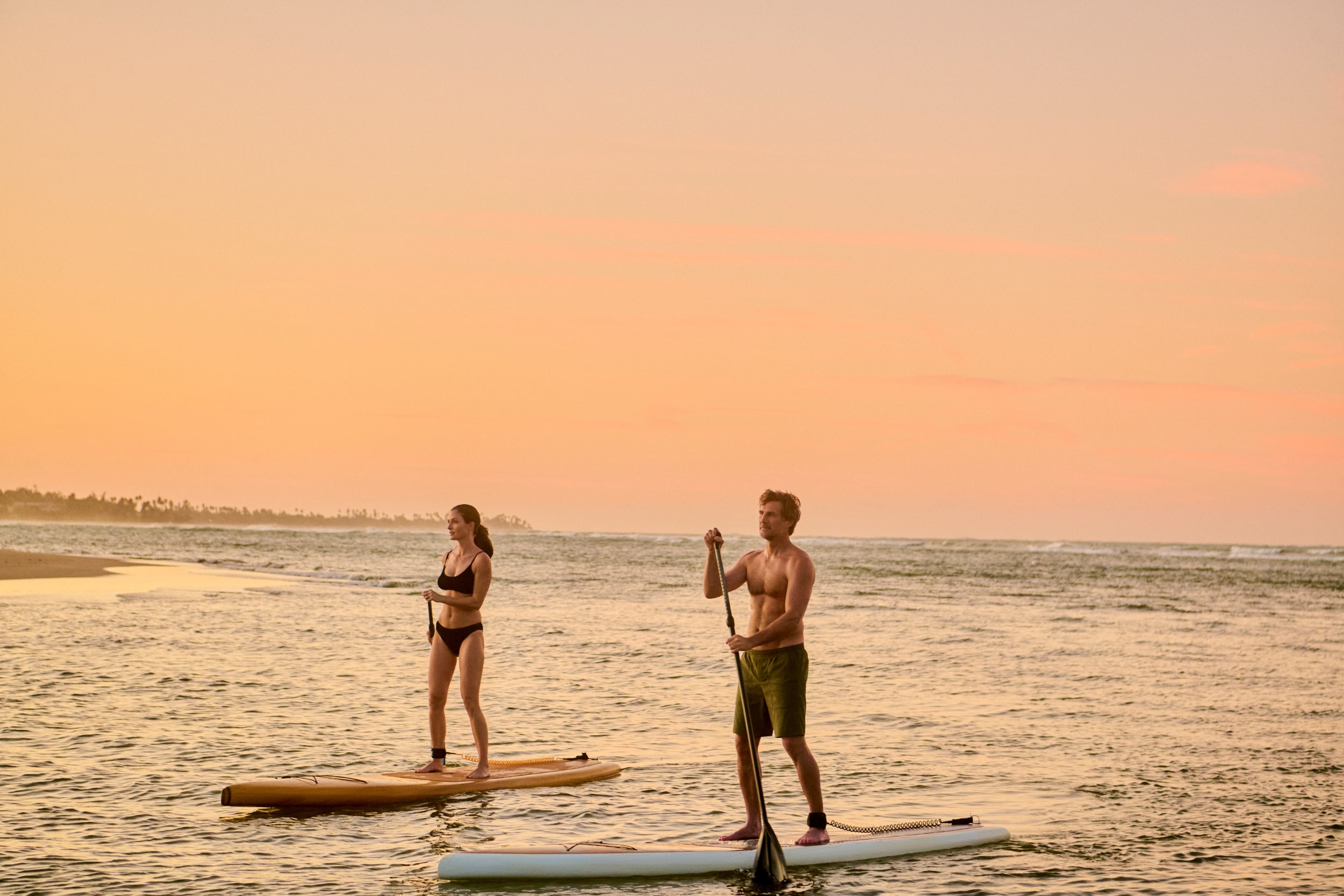A couple's idyllic escape on a secluded beach at Grand Reserve, where the golden sands and azure waters craft a private paradise in Puerto Rico