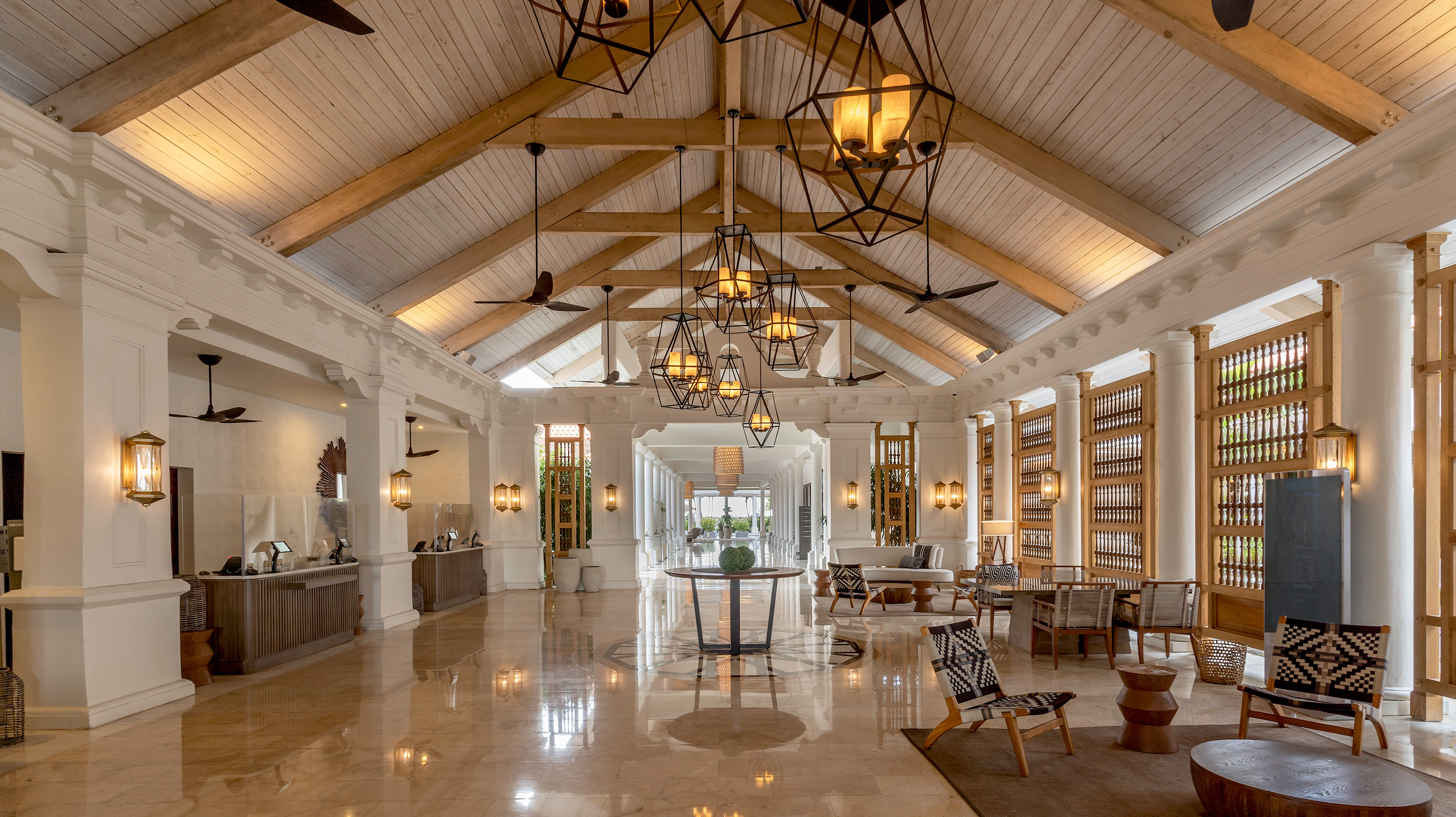 Interior view of the Hyatt Regency Grand Reserve lobby, featuring high ceilings with wooden beams, elegant chandeliers, and a polished reception area.